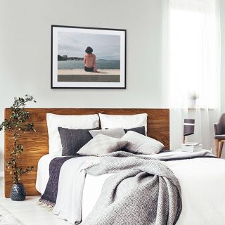 A framed print positioned above a bed.