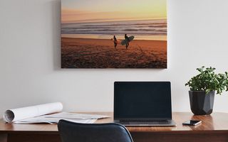 A canvas print positioned above a desk with a laptop.