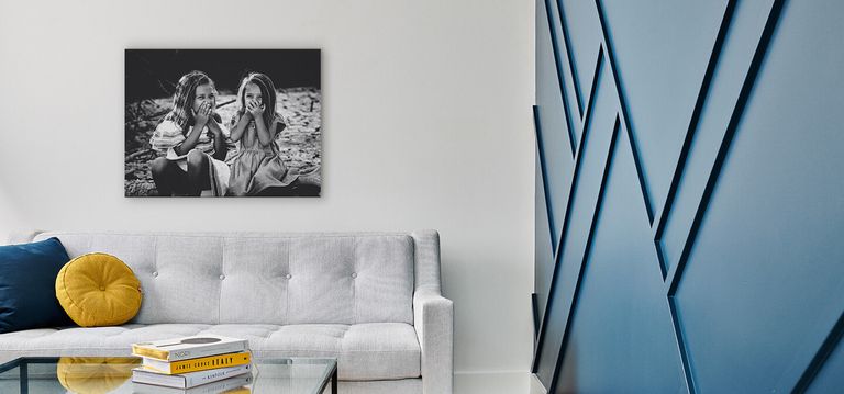 A canvas print hanging above a couch next to an accent wall.