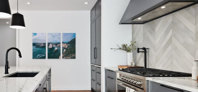 A triptych print hanging in a modern kitchen.