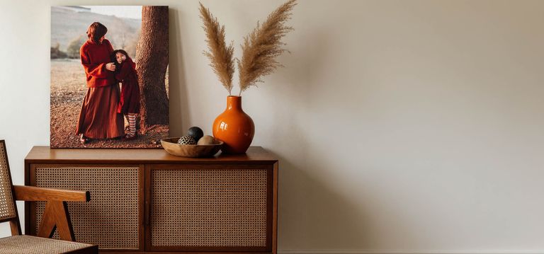 Two canvas print hanging in living room. One of young children playing near the lake, the other of a family portrait at the lake.