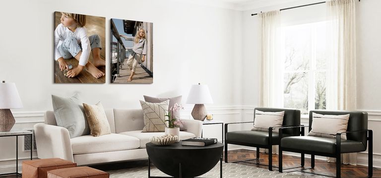 Two canvas print hanging over a couch. One of young child playing on the floor, the other of an older child leaning away from a dock railing