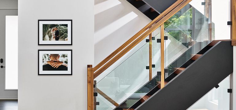 Two framed prints hanging on a wall next to a stair case.