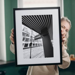 Lady holding up a black and white framed print.