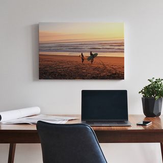 A canvas print positioned above a desk with a laptop