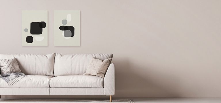 A generative art canvas print hanging above a couch next to an accent wall.
