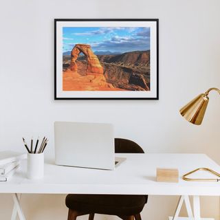 A framed print hanging above a computer desk.