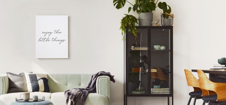 A canvas print hanging above a couch next to an accent wall.