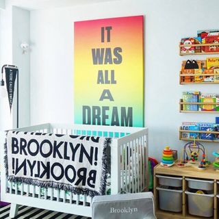 A large, colorful canvas print behind a crib.